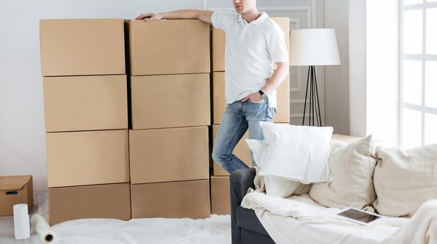 young man standing near boxes in his new apartment. photo with copy-space