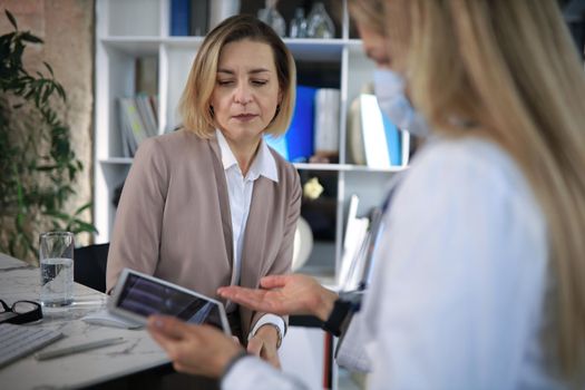 Middle aged female doctor therapist in consultation with patient in office