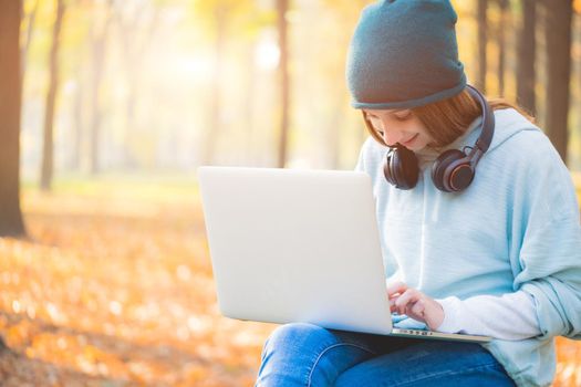 Cute girl working on laptop in autumn park