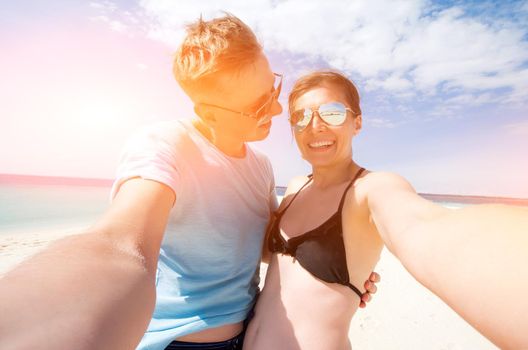 beautiful happy smiling couple making selfie on a beach, front view