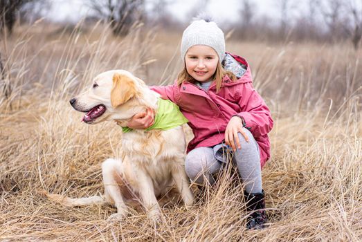 Little girl with cute dog in high dry grass