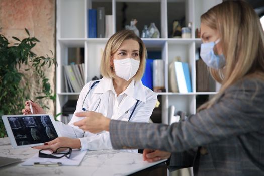 Middle aged female doctor therapist in consultation with patient in office