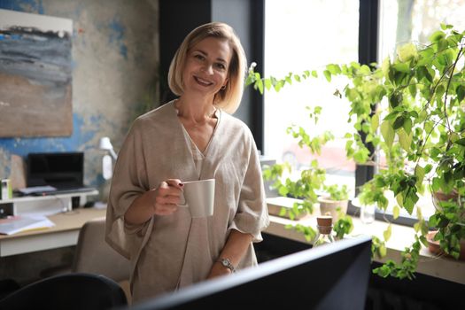 Attractive businesswoman standing near desk in the office.