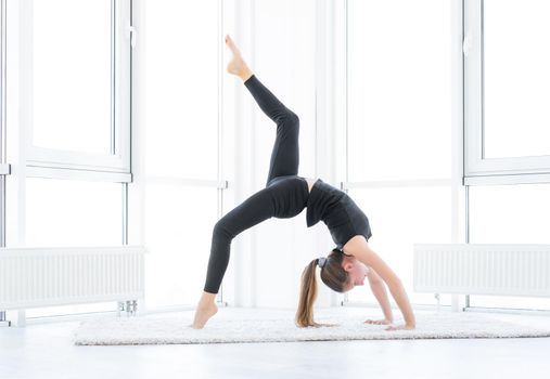 Sporty girl performing gymnastics in light room