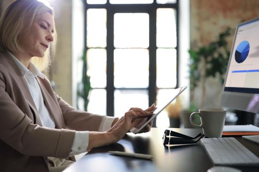 Beautiful business woman on the workplace using a digital tablet
