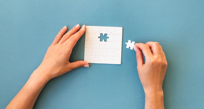 Hands with Small white square puzzle on a blue background