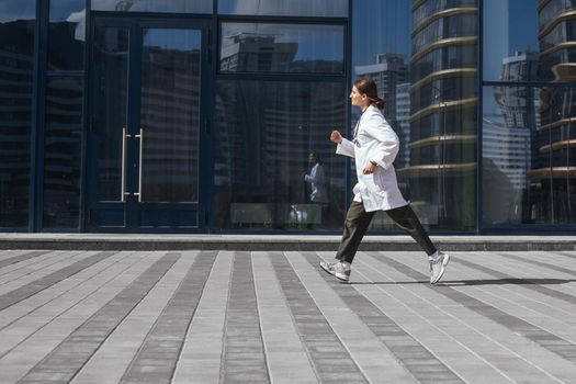 woman doctor runs down a city street. photo with a copy-space.