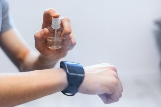 close up. casual man spraying disinfectant on his smart watch.