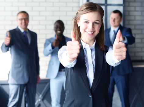 business concept - attractive businesswoman with team in office showing thumbs up