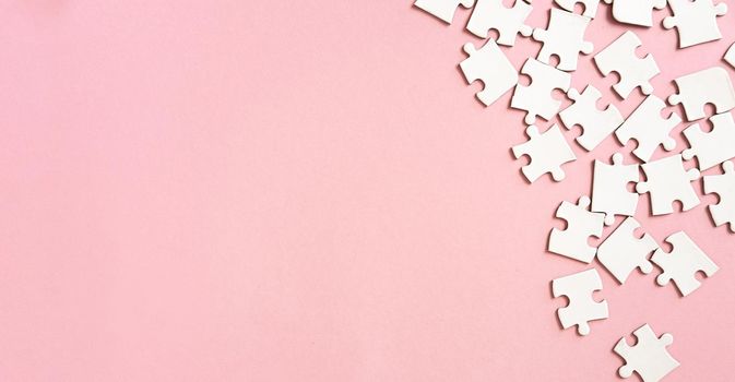 White jigsaw puzzle pieces in corner on pink background with copyspace