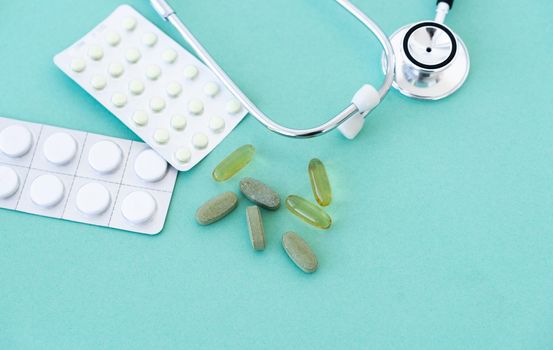 Phonendoscope and pills on blue background