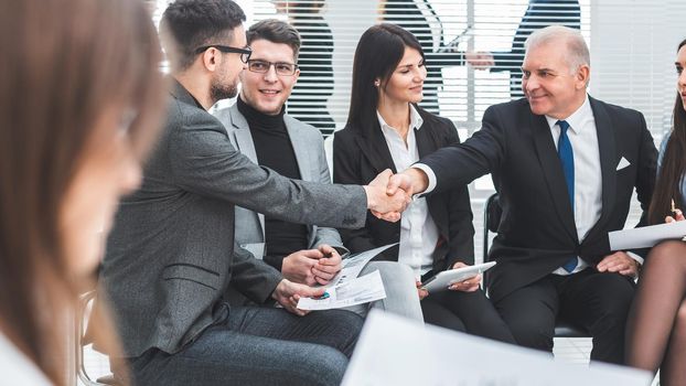boss shaking hands with an employee during a work meeting. the concept of teamwork