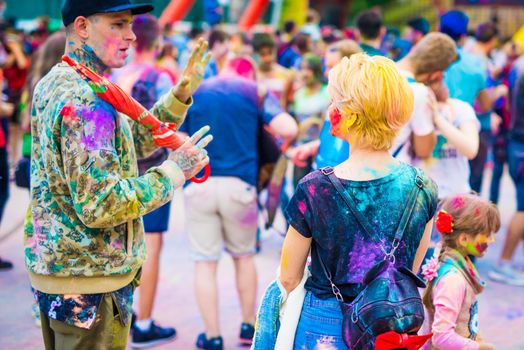 Khakiv, Ukraine - 19 May 2018: People sprinkle colorful paints during the festival. People with colorful faces celebrating holi fest