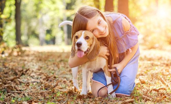 Cheerful kid hugging a dog in summer forest