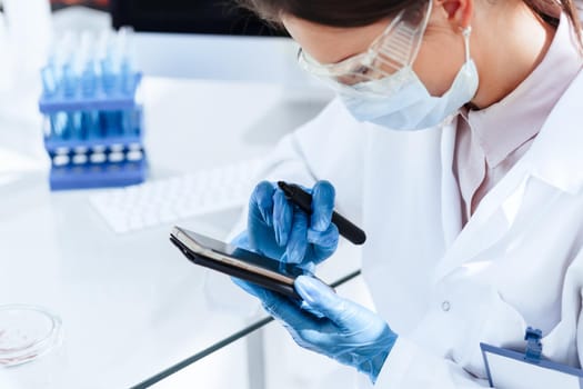 close up. female scientist using her smartphone in the workplace. photo with a copy-space.