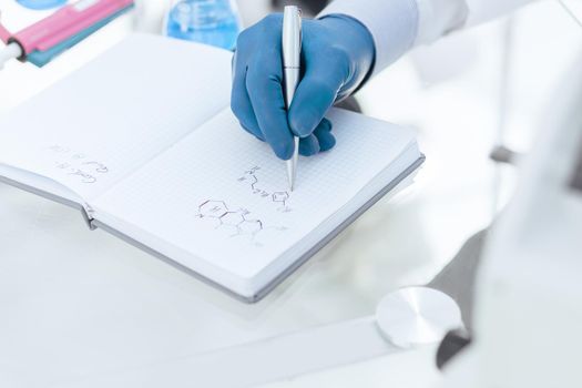 close up. female scientist writing research results in a notebook. science and health.