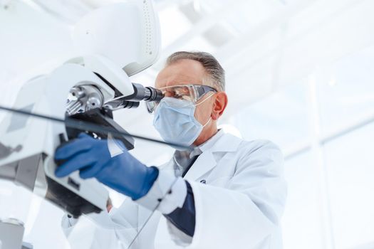 close up. serious scientist using a laboratory microscope. science and health protection.