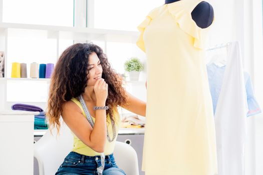 Tailor with mannequin in dress at sewing studio