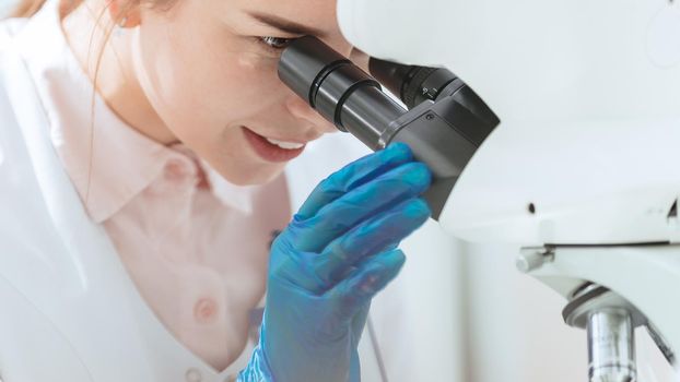 close up. female scientist looking through a microscope. science and health.