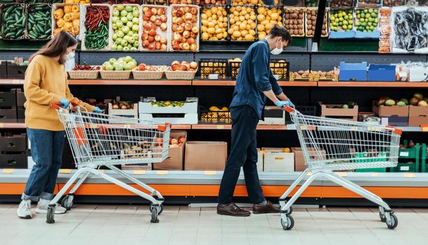 man and a woman with shopping carts in a supermarket during the quarantine period. photo with a copy-space