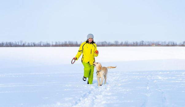 Smiling woman with cute young retriever dog on winter walk