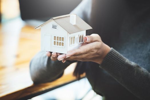 Female hand holding a house model, insurance concept and home loan