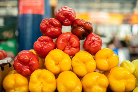 Close-up of arranged fresh red and yellow peppers at the market. Blurred background. Healthy eating concept.