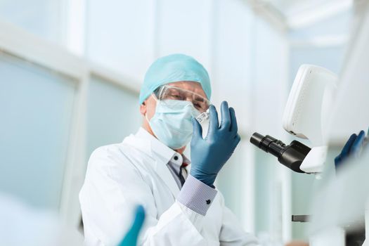 close up. scientist in with an ampoule sitting at a laboratory table . photo with a copy-space.
