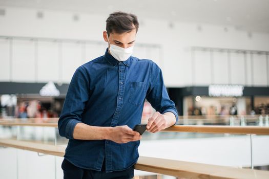 man in a protective mask with a smartphone standing on the street . photo with a copy of the space