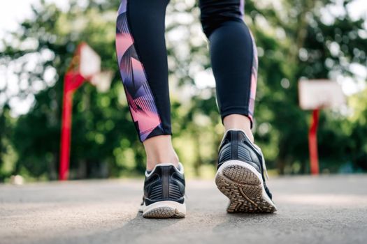 Closeup view on Young girl woman legs wearing sport leggings and shoes sneakers during exercising at stadium outdoors. Female person doing fitness workout outside