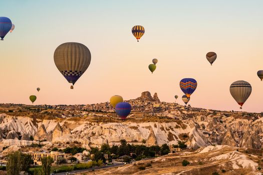 Colorful hot air balloons flying over beautiful valley in Cappadocia, Turkey on beautiful sunset sky