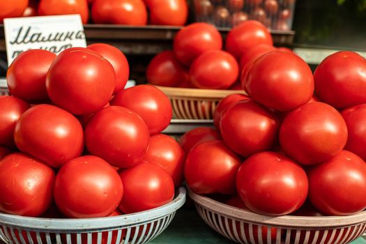 Stock photo of bright red grown tomatoes sorted in different baskets in a shop or at the market for sale. Grown in the countryside.