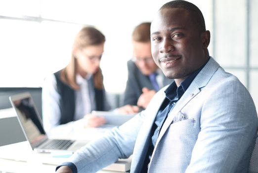 Portrait of smiling African American business man with executives working in background