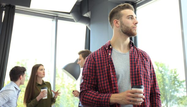 Happy attracive young businessman drinking coffee in office.