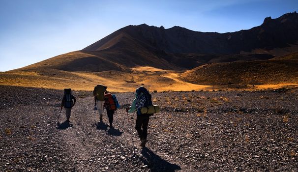 Hiking on volcano Erciyes in Turkey in sunrise time. People with backpacks climbing to the top of mountain. Scenery Kayseri landscapes