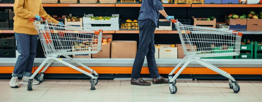 man and a woman with shopping carts in a supermarket during the quarantine period. photo with a copy-space