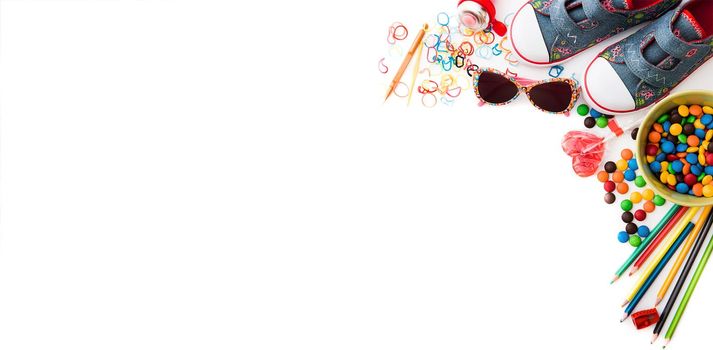 white backgrounnd with colourful kids's sweets and stationery with copyspace. Childhood concept.