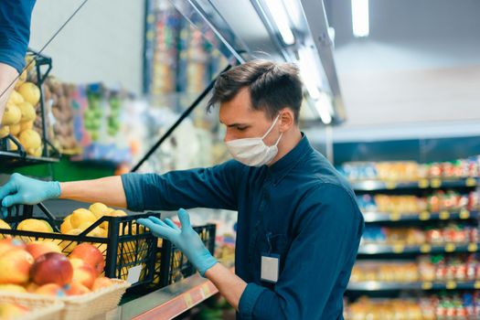 seller in a protective mask standing in front of the counter with fruit. coronavirus in the city