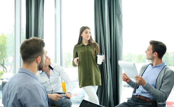 Group of young modern people in smart casual wear having a brainstorm meeting in the creative office.