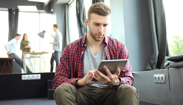 Smiling young man using digital tablet in the office.