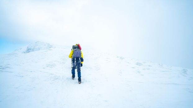 Lonely tourist trekking winter mountain top covered with snow