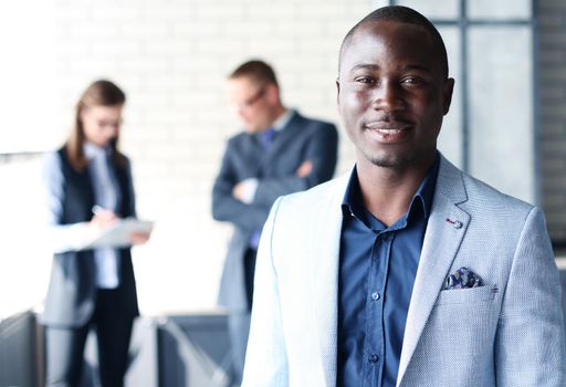 Portrait of smiling African American business man with executives working in background
