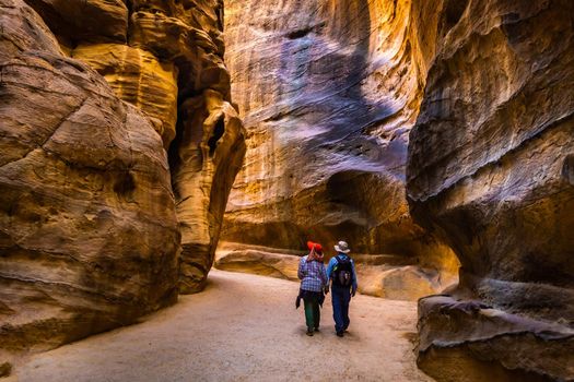 Group of people between sandstone rocks at narrow path in Petra, Jordan