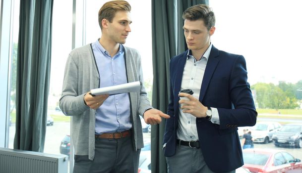 Two young modern men discussing work in the office