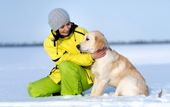 Beautiful girl with lovely young retriever dog outside in winter