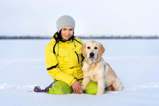 Young woman with lovely retriever puppy dog in winter