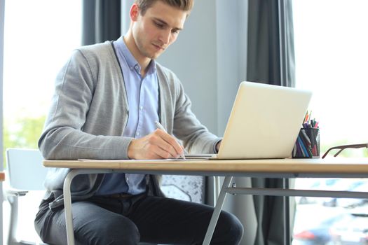 Young modern business man working using laptop while sitting in the office