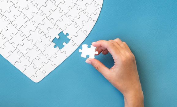 Hand with white puzzle. White details of puzzle on blue background.