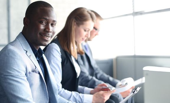 Portrait of smiling African American business man with executives working in background
