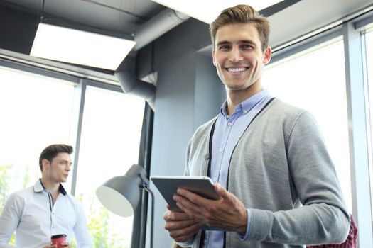 Smiling young man using digital tablet in the office.